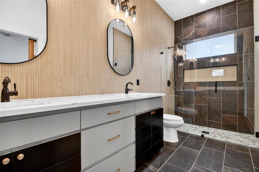Bathroom with double vanity, a shower stall, and tile walls