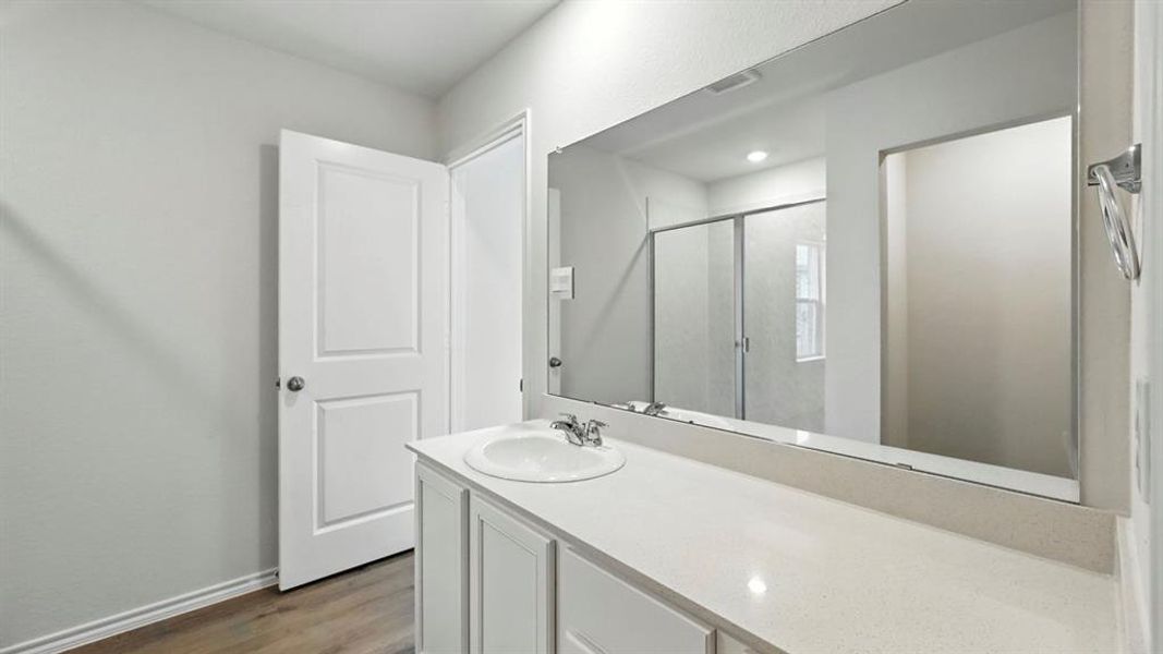 Bathroom vanity featuring a single basin sink, light-toned countertop, and white cabinetry Bathroom vanity featuring a single basin sink, light-toned countertop, and white cabinetry