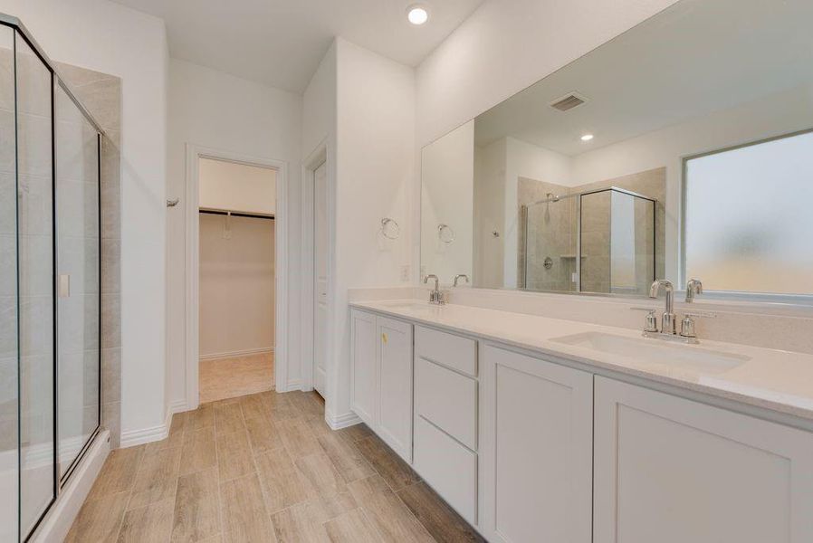 Bathroom with hardwood / wood-style flooring, a shower with door, and dual bowl vanity