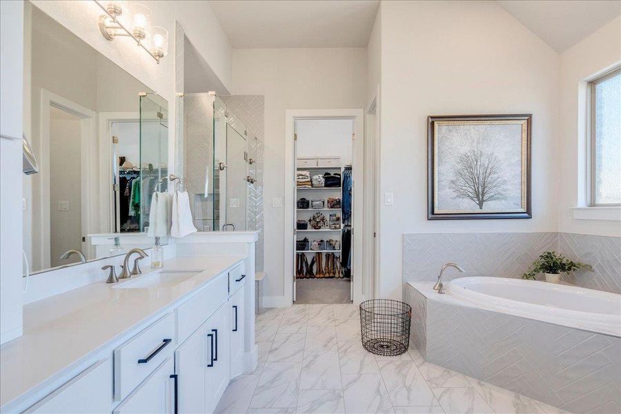 Bathroom with a spacious closet, a shower stall, vanity, a garden tub, and light marble finish floors Bathroom with a spacious closet, a shower stall, vanity, a garden tub, and light marble finish floors
