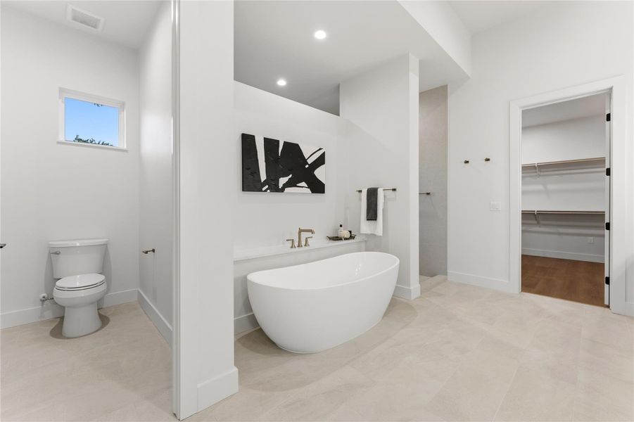 Bathroom with a spacious closet, a freestanding tub, and recessed lighting
