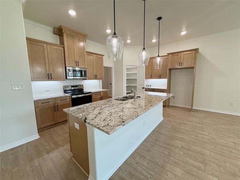 Kitchen with stainless steel appliances, ornamental molding, tasteful backsplash, light wood-style flooring, and light stone countertops