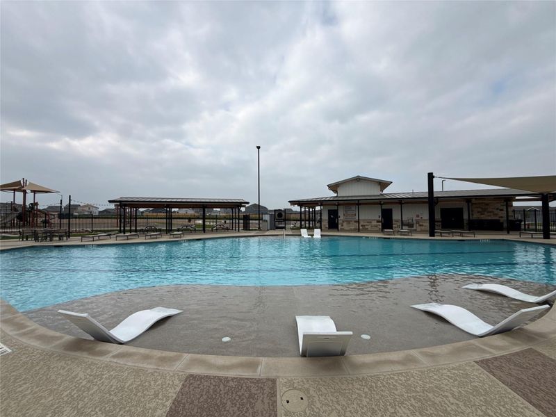 Community swimming pool featuring an integrated sun shelf with in-water loungers
