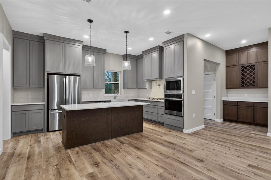 Cozy and stunning beautiful kitchen features gas cooktop, island, pot filler, oven/microwave built-in, dishwasher, quartz countertops, apron-front farm sink, refrigerator, walk-in pantry and plenty of storage in cabinets!