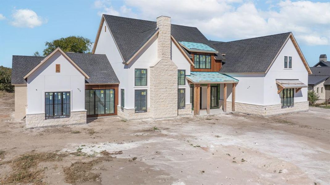 View of front facade with roof with shingles, stone siding, a chimney, and stucco siding View of front facade with roof with shingles, stone siding, a chimney, and stucco siding