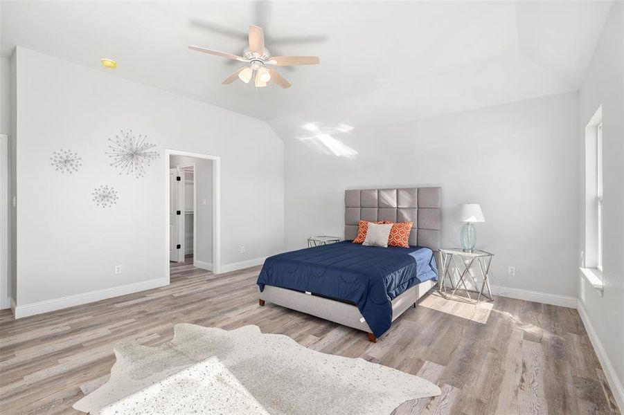 Bedroom featuring ceiling fan, vaulted ceiling, and light wood-type flooring