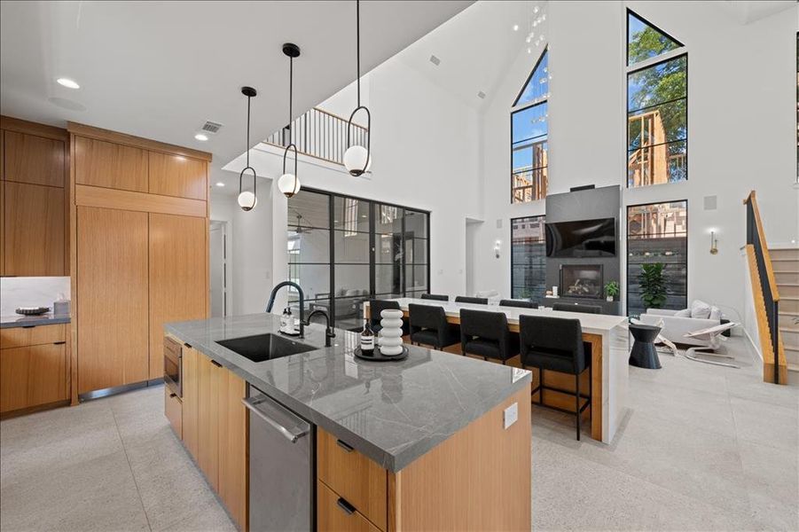 Kitchen featuring modern cabinets, dark stone countertops, open floor plan, hanging light fixtures, and a spacious island