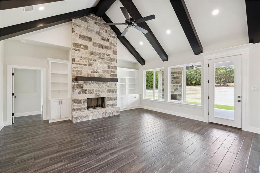 Unfurnished living room with a fireplace, beamed ceiling, built in shelves, and dark hardwood / wood-style flooring