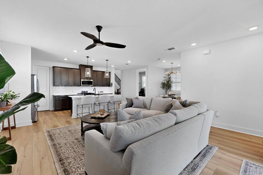 Living area with recessed lighting, light wood-type flooring, a ceiling fan, a chandelier, and stairway