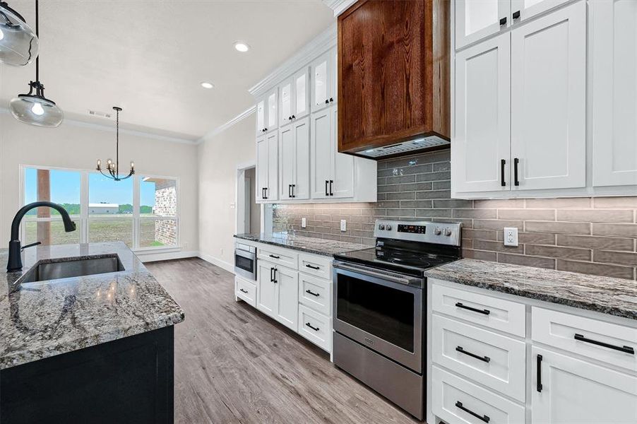 Kitchen with light wood-type flooring, stainless steel electric stove, tasteful backsplash, ornamental molding, and white cabinets