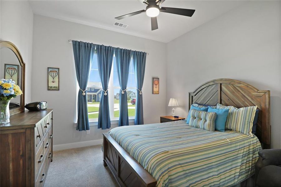 Bedroom featuring baseboards, light colored carpet, and a ceiling fan Bedroom featuring baseboards, light colored carpet, and a ceiling fan