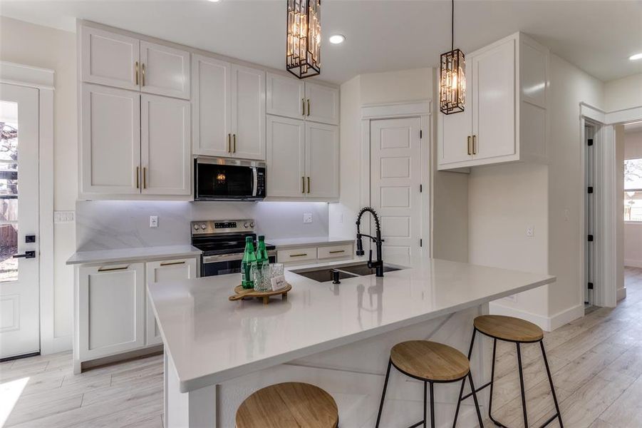 Kitchen with a sink, white cabinets, a notable chandelier, and stainless steel appliances