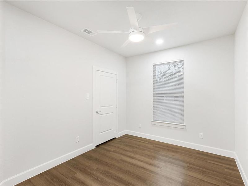 Empty room with dark wood-style flooring and ceiling fan
