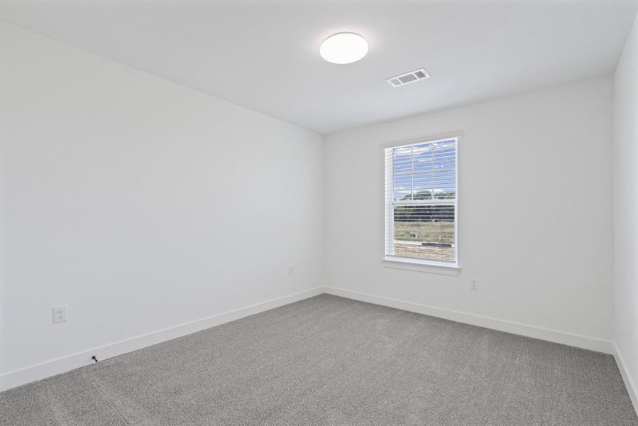 Neutral wall finishes with a window featuring blinds, complemented by a round ceiling-mounted light fixture and gray carpeting