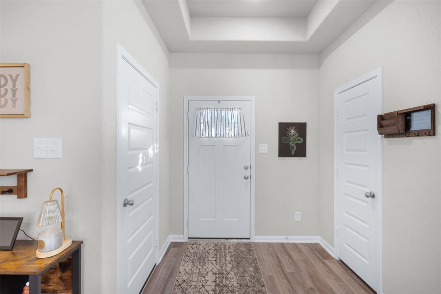 This photo shows a welcoming entryway. The space features neutral walls, and wood flooring, creating a cozy and inviting atmosphere.