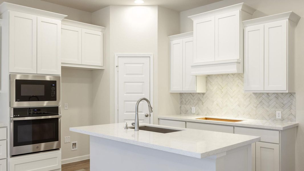 Kitchen with stainless steel oven, white cabinetry, a sink, cooktop, and decorative backsplash