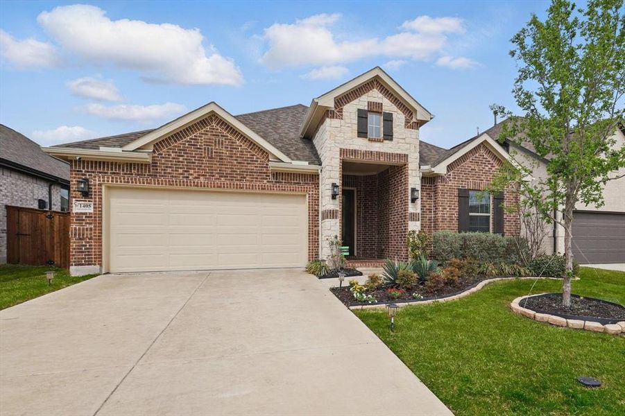 View of front of house with an attached garage, a shingled roof, concrete driveway, and brick siding
