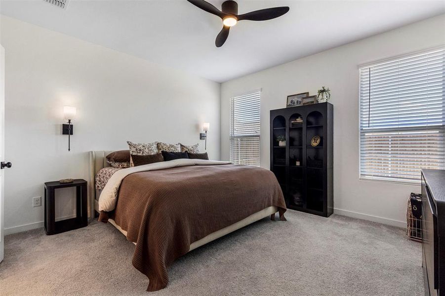Bedroom featuring soft gray carpet flooring, white walls, and a ceiling fan with integrated lighting Bedroom featuring soft gray carpet flooring, white walls, and a ceiling fan with integrated lighting