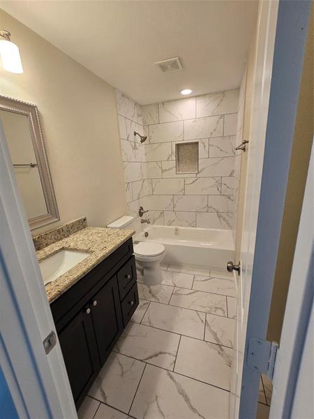 Bathroom featuring marble finish flooring, toilet, vanity, shower / bath combination, and recessed lighting