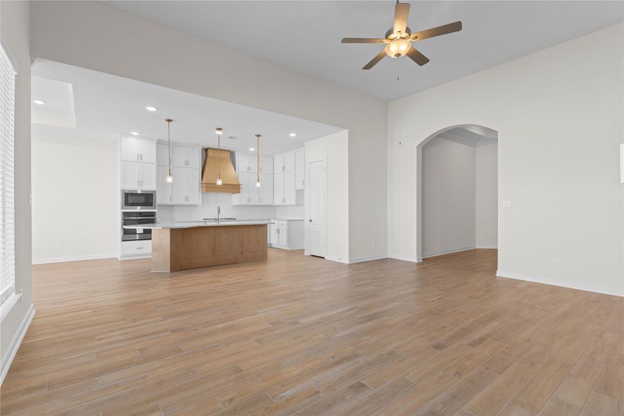 From this perspective, the home truly shines with its generous living area, graceful archways, and smooth transitions between spaces, with wood like tile flooring providing a polished foundation that ties the entire main living area together beautifully.
