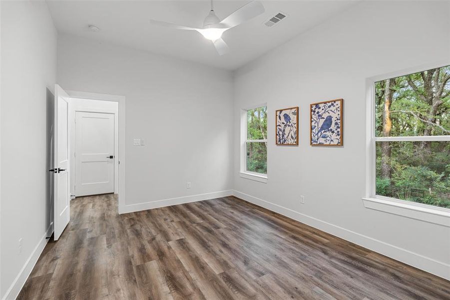 Spare room featuring ceiling fan, plenty of natural light, and dark wood-type flooring