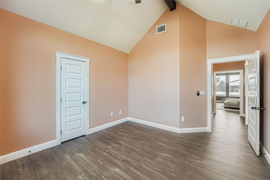 Empty room featuring wood-type flooring, high vaulted ceiling, and beamed ceiling