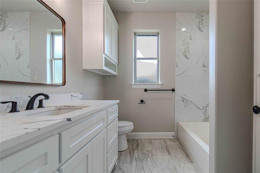 Full bathroom featuring toilet, vanity, and plenty of natural light