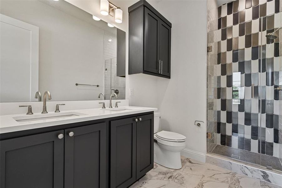 Bathroom featuring toilet, vanity, and a shower with door