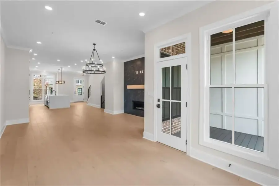 Light wood-finish flooring throughout, recessed lighting, and a dark decorative fireplace with a wood mantle