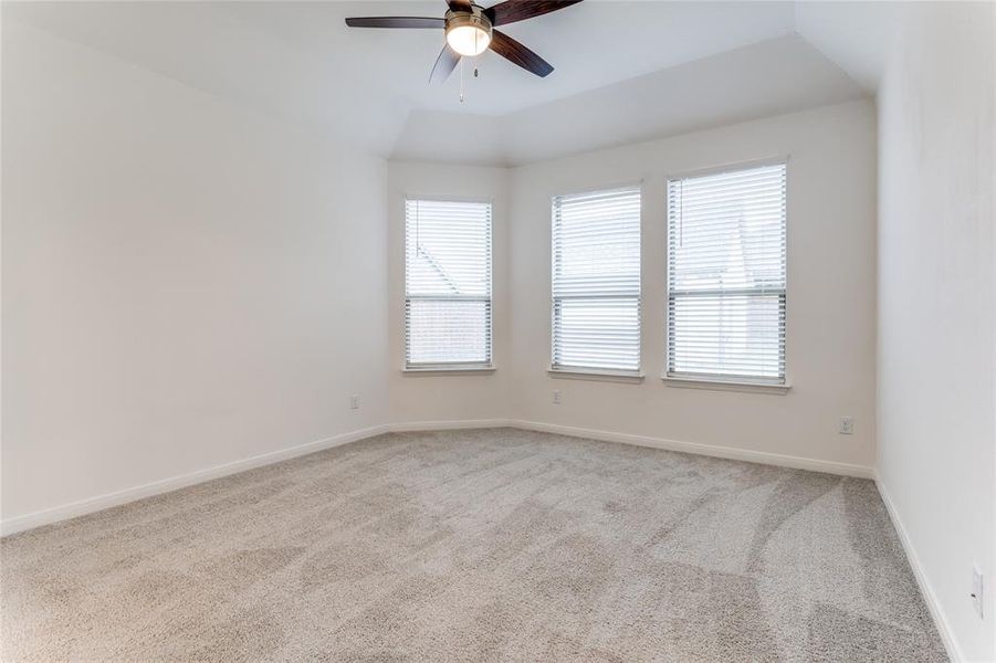 Carpeted empty room featuring ceiling fan and vaulted ceiling