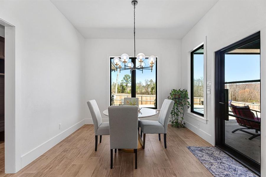 Dining room featuring baseboards, an inviting chandelier, light wood finished floors, and plenty of natural light Dining room featuring baseboards, an inviting chandelier, light wood finished floors, and plenty of natural light