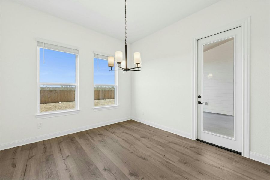 Unfurnished dining area featuring suspended lighting and wood finished floors