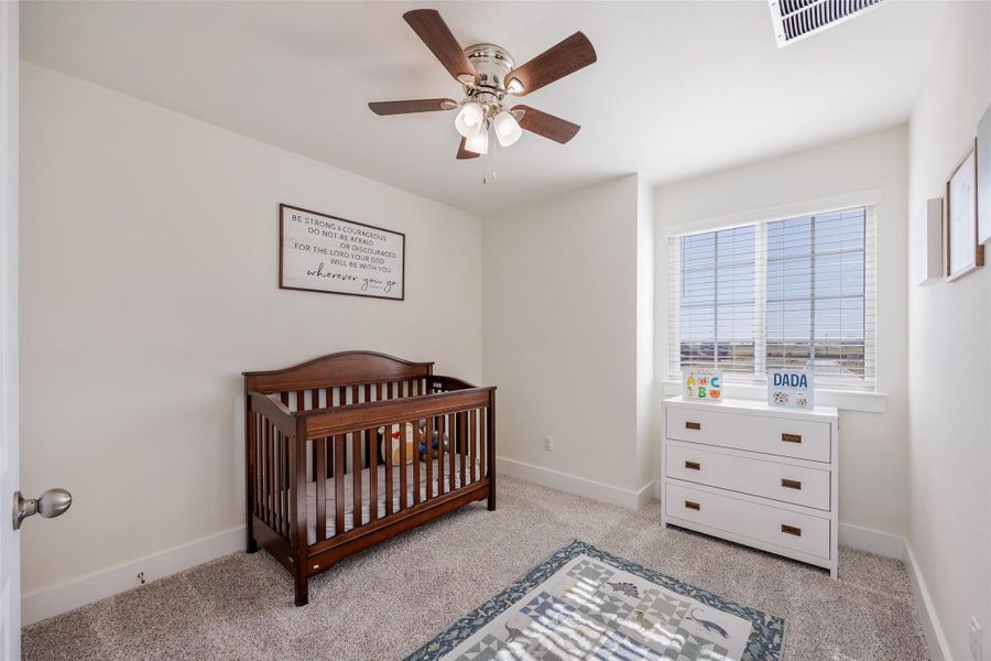 Bedroom with a crib, light carpet, and a ceiling fan Bedroom with a crib, light carpet, and a ceiling fan