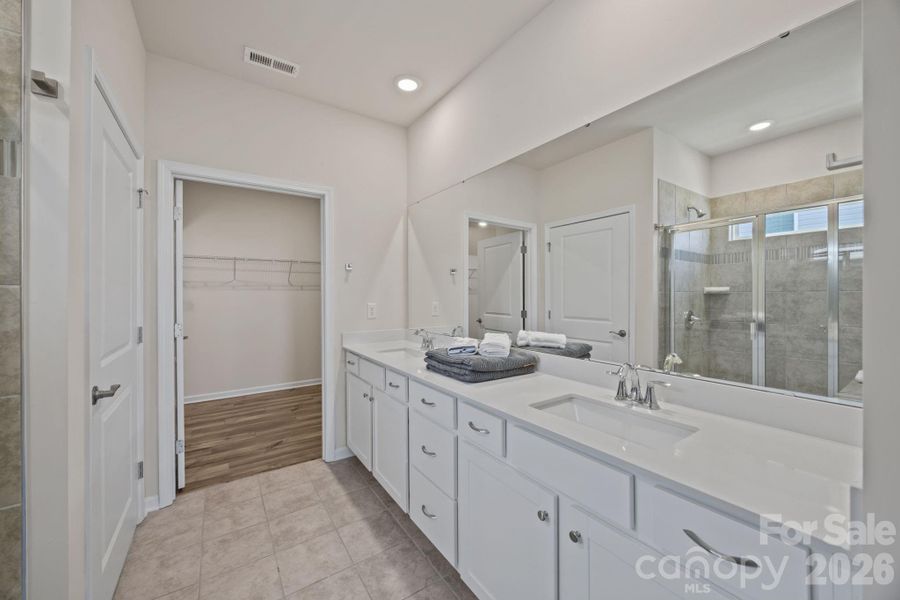 PRIMARY ensuite full bath with long quartz countertop featuring popular squared sinks and loads of room. Separate doored toilet facility, tiled floors and ample sized shower.  Door leads to expansive closet! Enjoy!