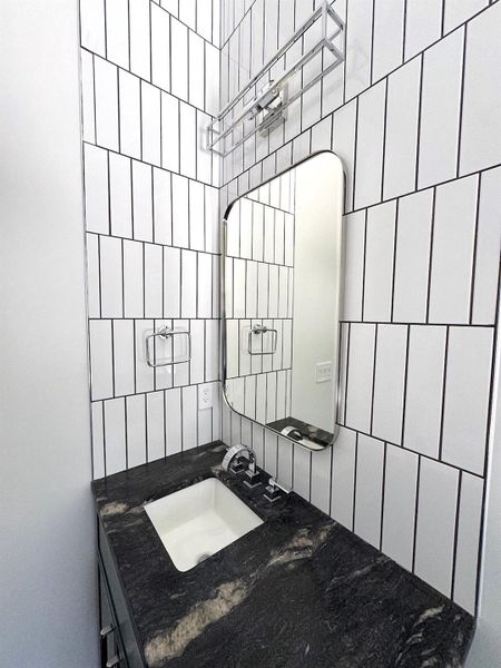 Bathroom with tiled shower, backsplash, tile walls, and a sink