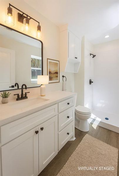 Full bath featuring vanity, dark wood finished floors, and a shower
