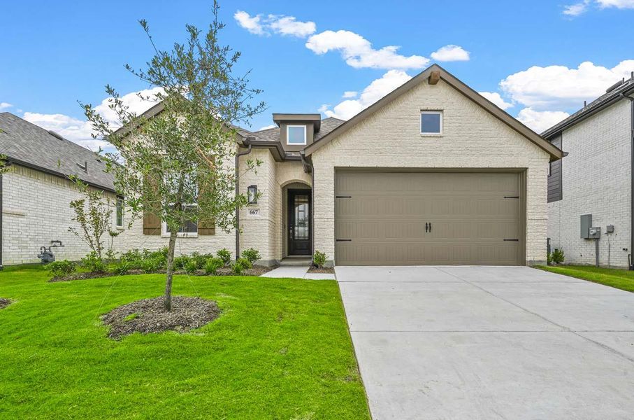 French provincial home featuring concrete driveway, a garage, brick siding, and a front yard