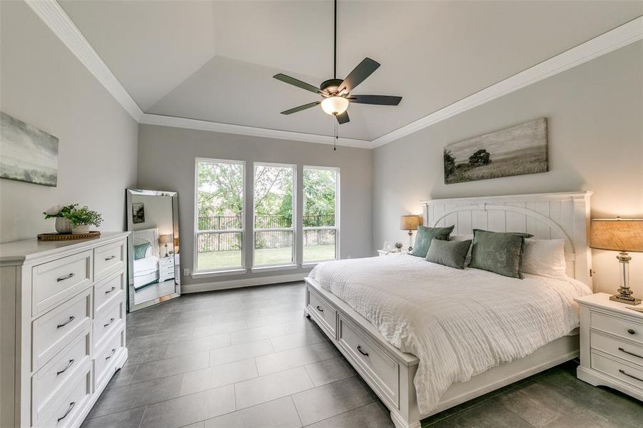 Tiled Primary bedroom with ceiling fan and crown molding