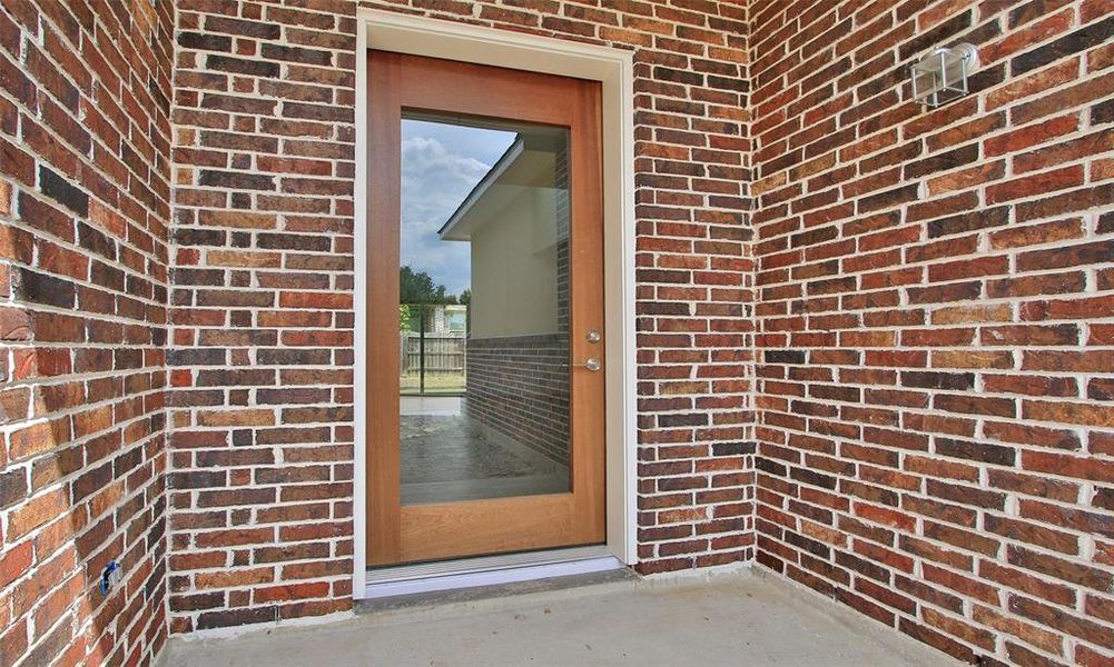 This is a bright, open-concept living space featuring high ceilings with skylights, modern tile flooring, and a clear view to the backyard through large windows and glass doors. A contemporary staircase leads to additional space above.