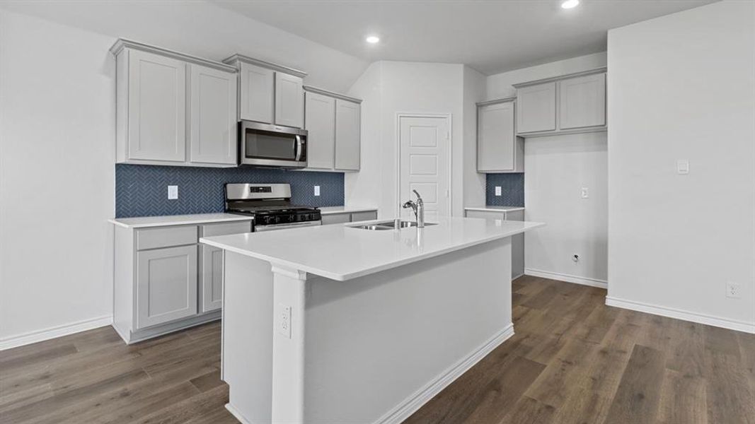 Kitchen featuring stainless steel appliances, a kitchen island with sink, recessed lighting, dark wood-type flooring, and backsplash