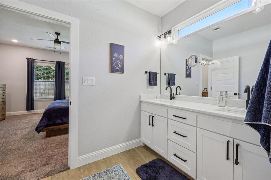 Ensuite bathroom with double vanity, light wood-style flooring, and ceiling fan Ensuite bathroom with double vanity, light wood-style flooring, and ceiling fan