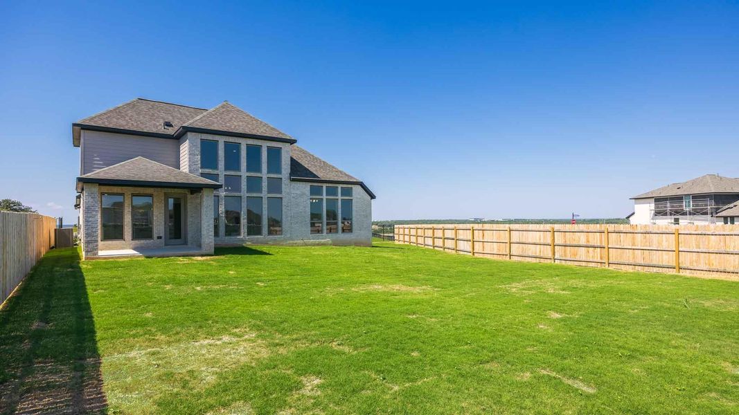 Back of house with a fenced backyard, roof with shingles, and a patio area Back of house with a fenced backyard, roof with shingles, and a patio area