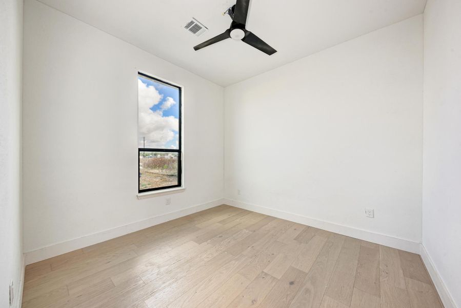 Clean lines and light wood flooring define this versatile secondary bedroom space.