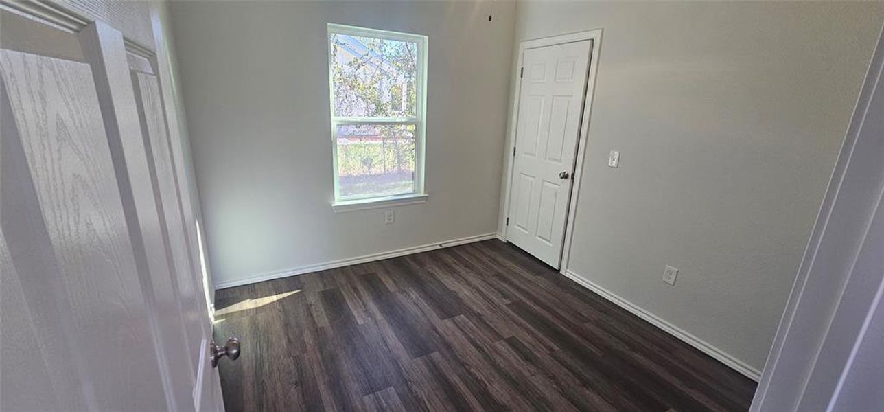 Unfurnished bedroom featuring baseboards and dark wood finished floors