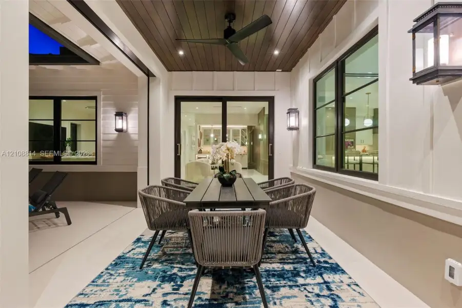 Covered patio featuring a wood-plank ceiling, matte black ceiling fan, recessed lighting, wall-mounted exterior lanterns, and multi-panel sliding glass doors Covered patio featuring a wood-plank ceiling, matte black ceiling fan, recessed lighting, wall-mounted exterior lanterns, and multi-panel sliding glass doors