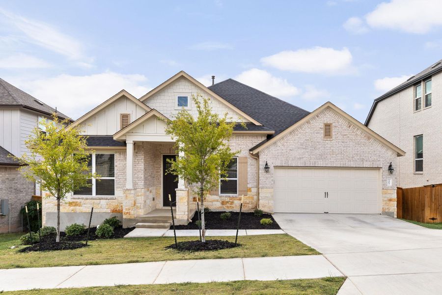 View of front of property featuring a garage, concrete driveway, stone siding, and board and batten siding