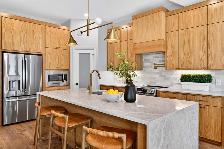Kitchen with stainless steel appliances, a kitchen bar, light stone counters, and modern cabinets