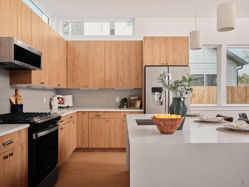 Kitchen with stainless steel appliances, light wood finish cabinets, light stone countertops, light wood-style floors, and pendant lighting