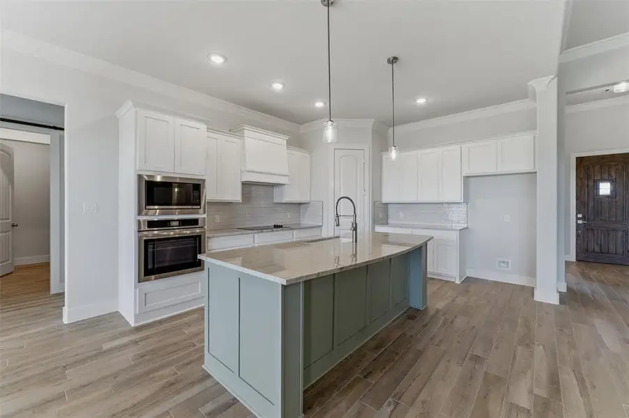 Kitchen featuring a large island with a countertop, integrated sink, and pendant lighting