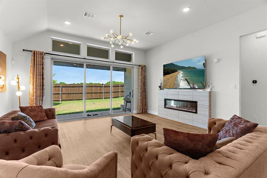 Living room featuring a chandelier, a tiled fireplace, wood finished floors, recessed lighting, and lofted ceiling Living room featuring a chandelier, a tiled fireplace, wood finished floors, recessed lighting, and lofted ceiling